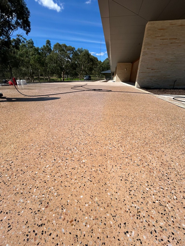 Sealed exposed-aggregate concrete forecourt in golden tones at commercial site