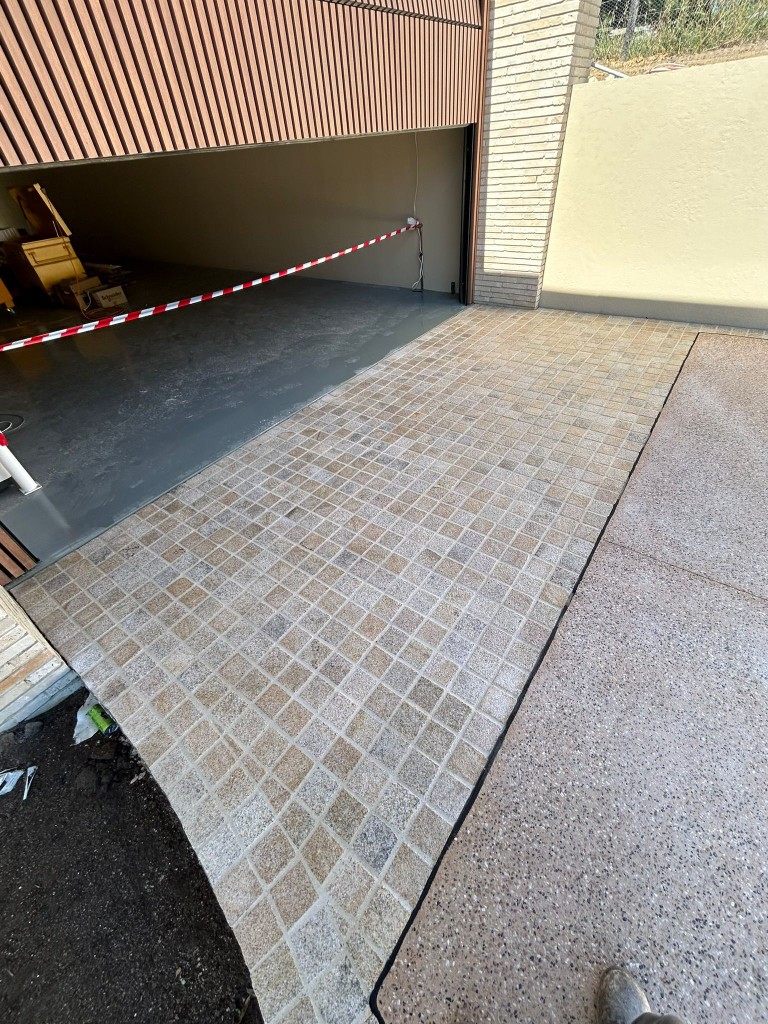 Sandstone mosaic-tiled driveway entry sealed at residential property