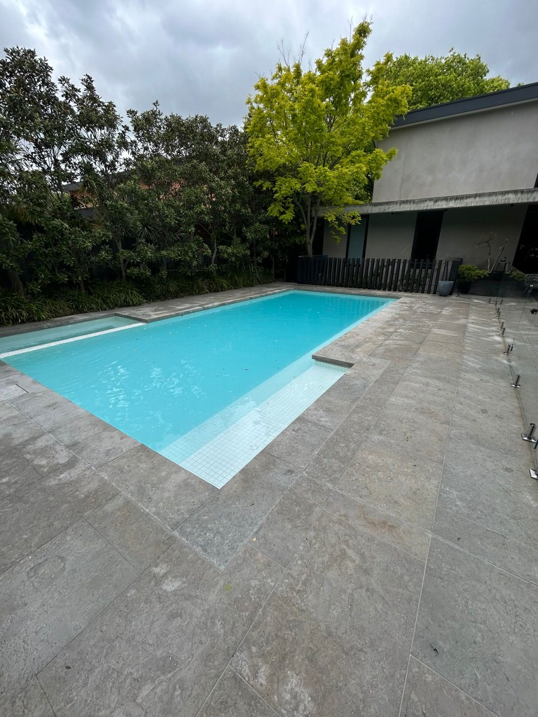Limestone-tiled pool surround at modern luxury home in Melbourne