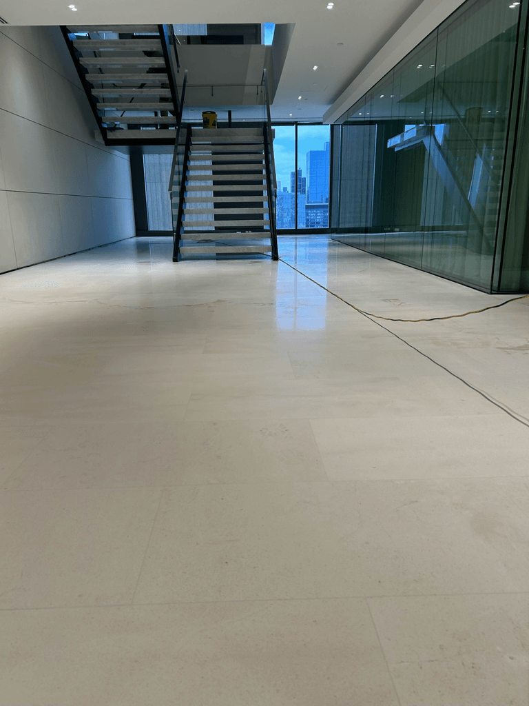 Honed limestone tile floor in Melbourne high-rise penthouse with floating staircase and city skyline view