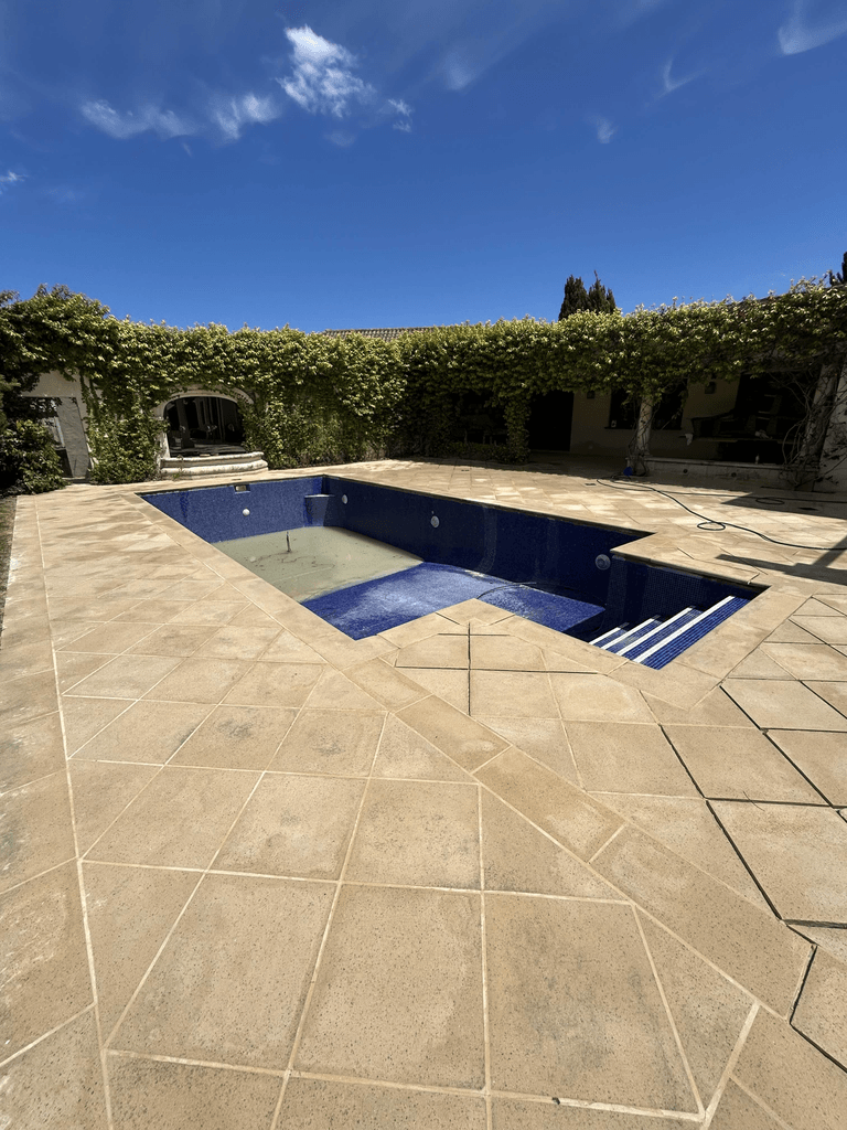 Sandstone pool surround with vine-covered pergola and blue mosaic tile pool at Mediterranean-style Melbourne home