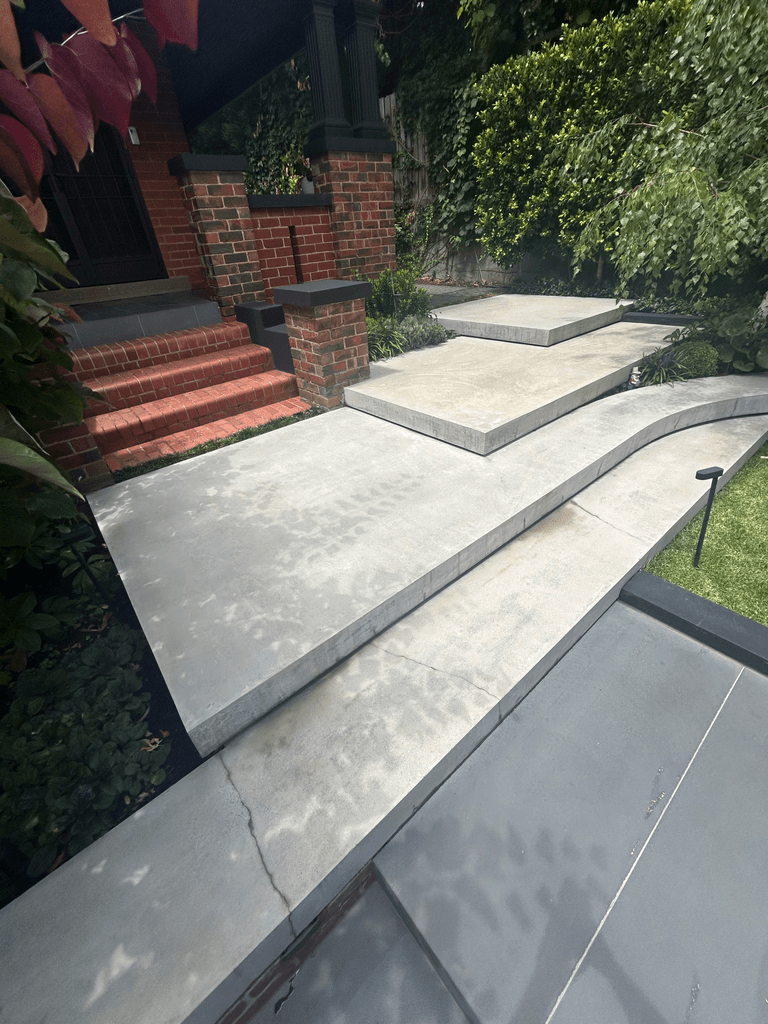 Floating concrete steps and curved entry platform at heritage brick Melbourne home