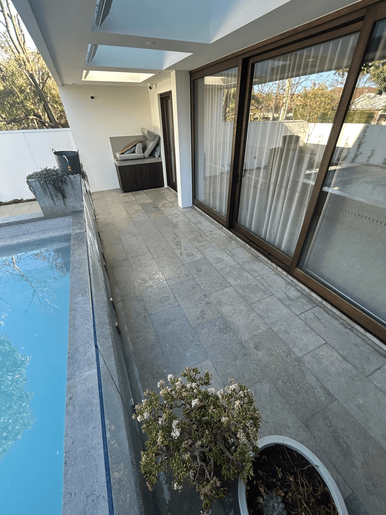 Bluestone-look stone paving pool surround with glass balustrade at modern Melbourne home