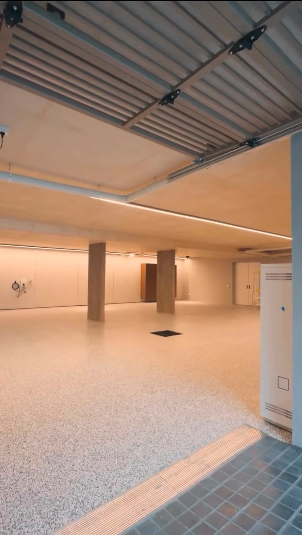 Cream speckle polished floor in finished underground space with timber joists and linear LED strip