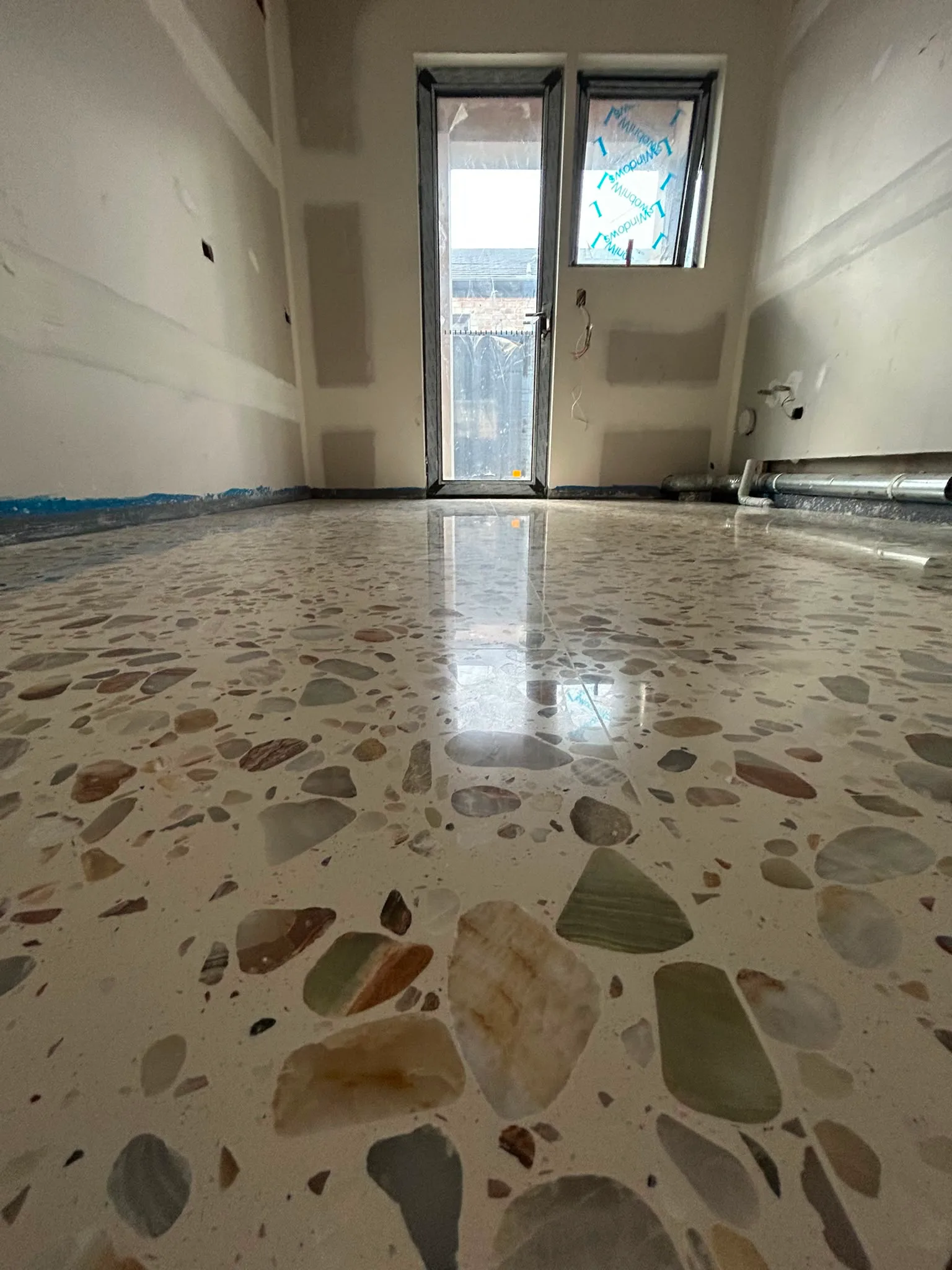 Freshly polished terrazzo floor with large rounded river-stone aggregate in cream binder, residential new build
