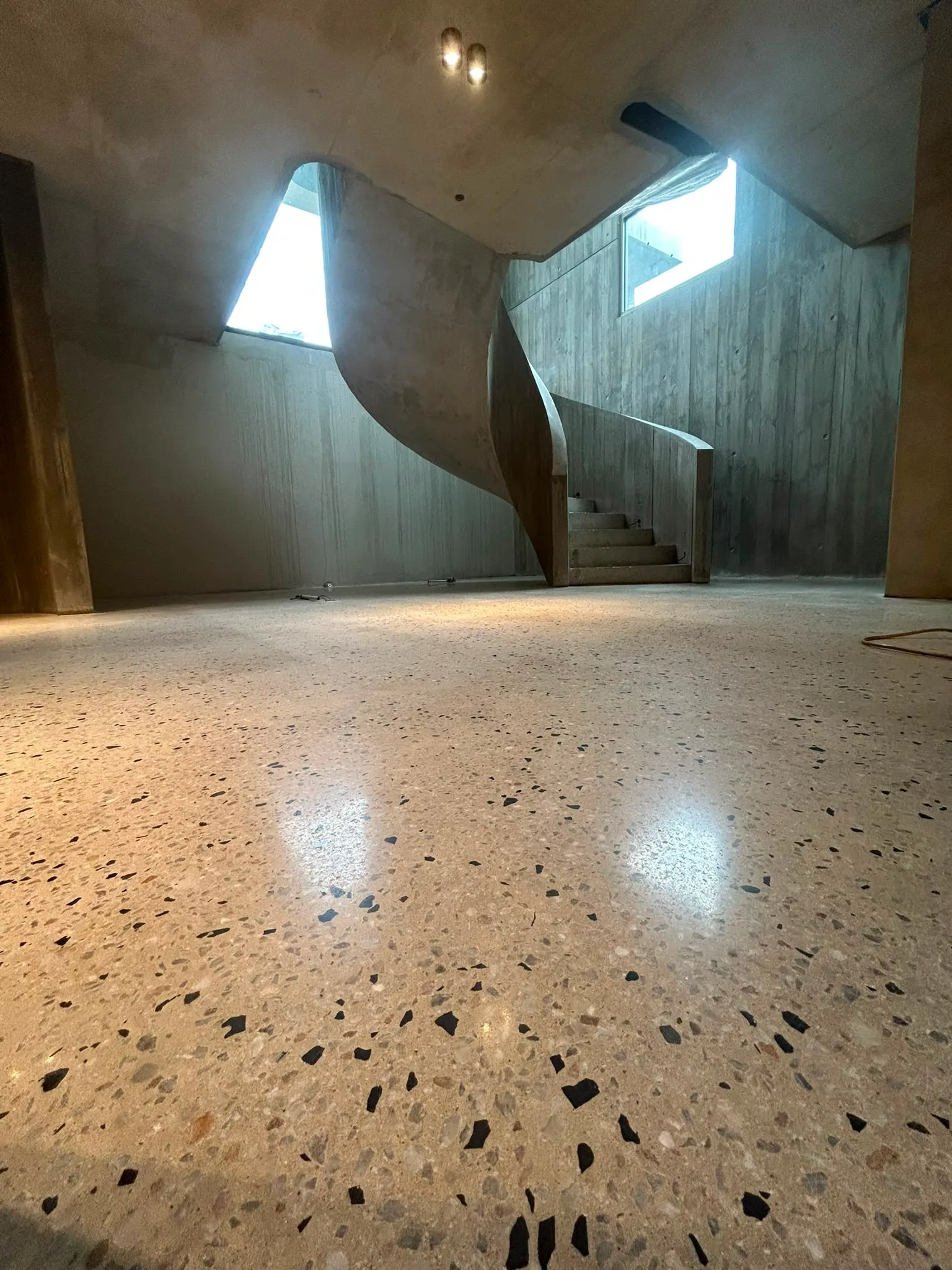 Wide view of curved concrete staircase new build showing freshly polished floor with fine dark aggregate, Claraseal Melbourne