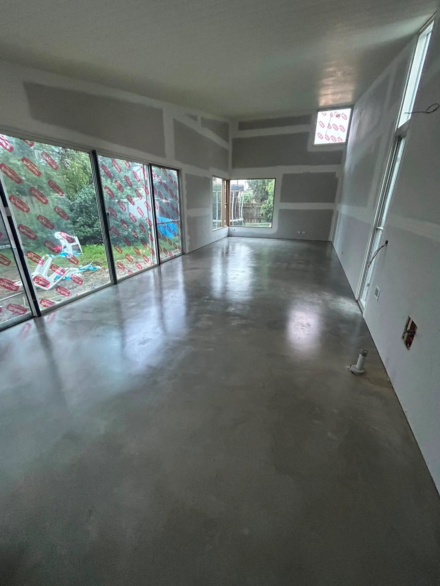 Grey polished concrete floor in residential new build with moderate gloss, room under construction
