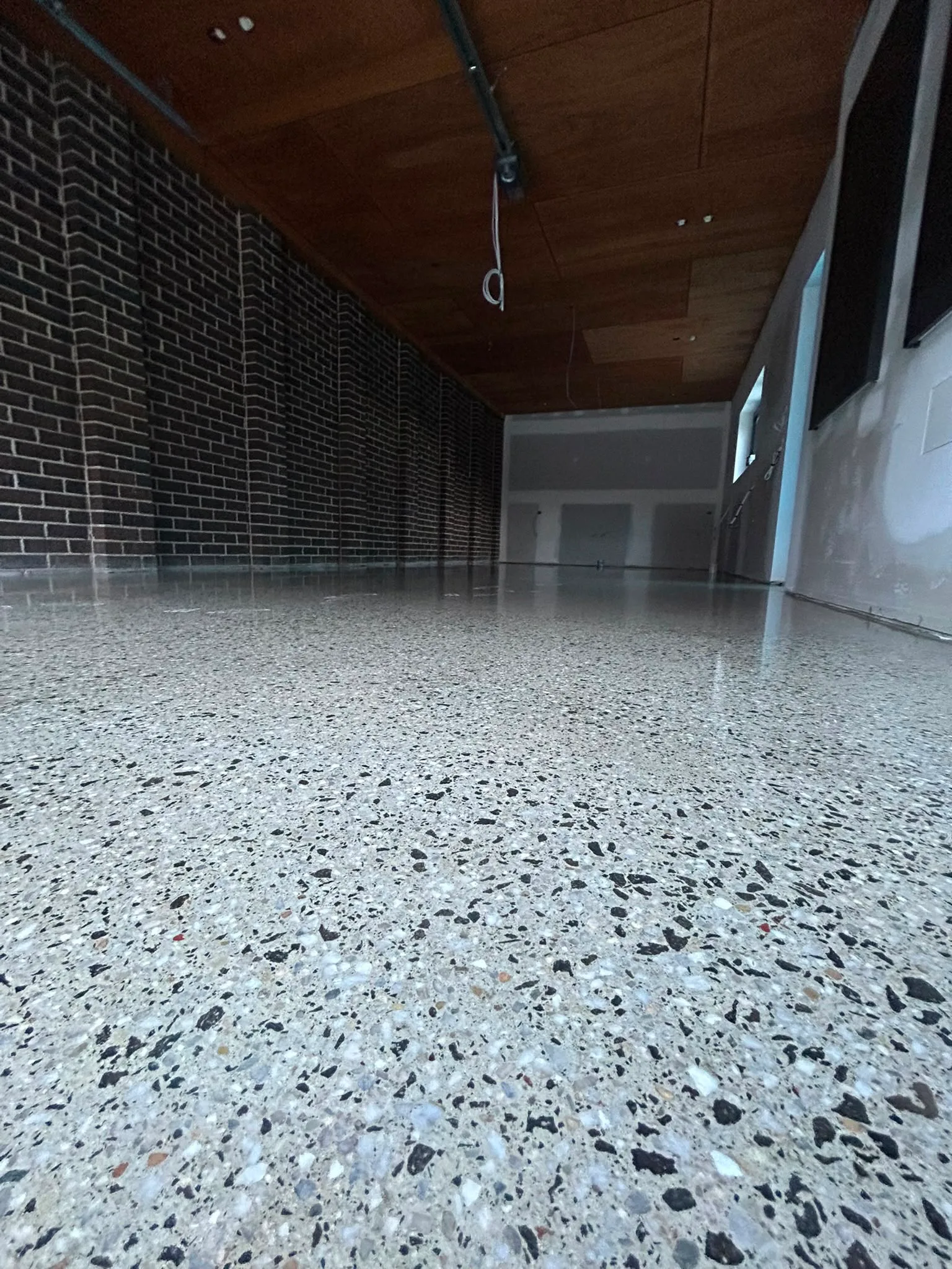 Dense black and white terrazzo floor in brick-wall and timber-ceiling space, Claraseal Melbourne