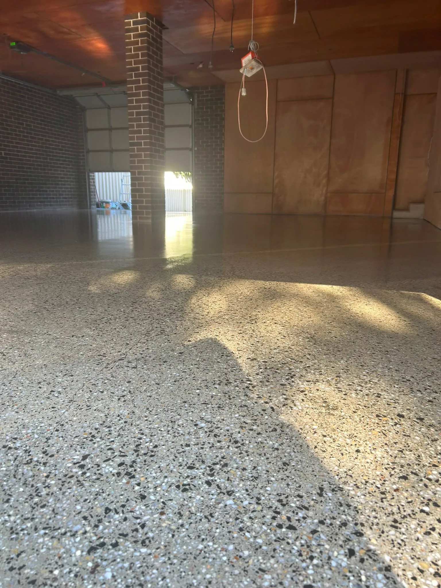 Black and white terrazzo floor in brick and timber interior with dappled natural light, Claraseal Melbourne