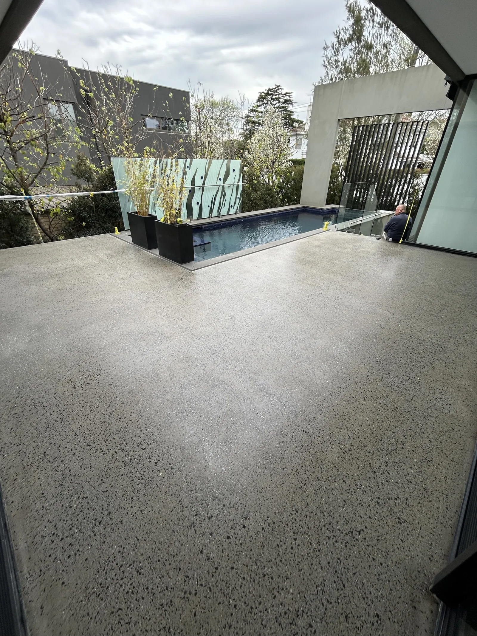Concrete deck with exposed stone aggregate beside a pool at a modern Melbourne home