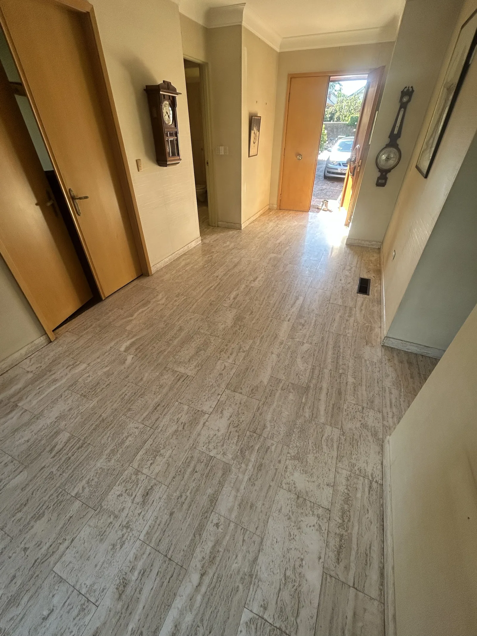Travertine tile entry hall with timber doors, the front door open to the driveway