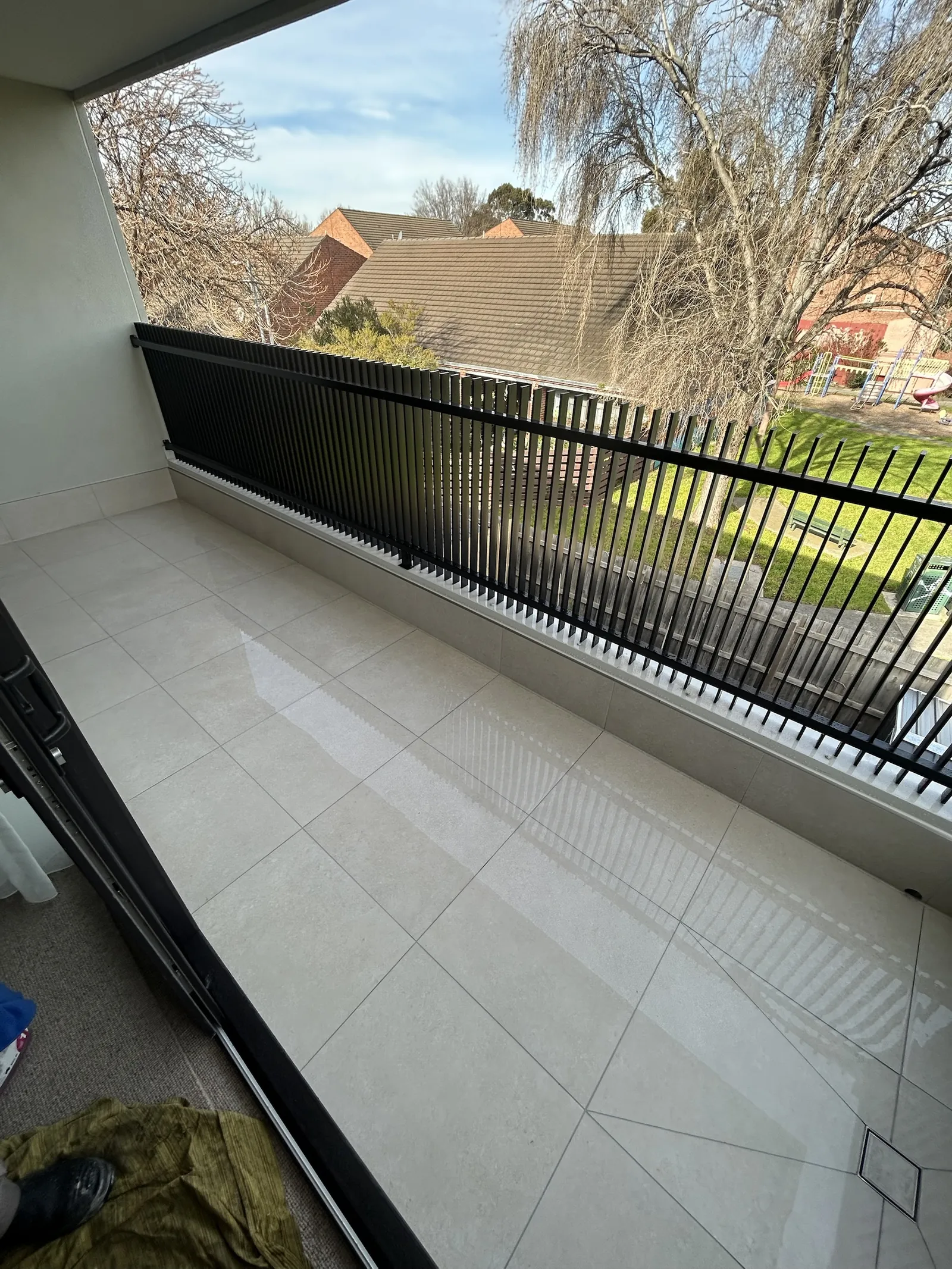 Long tiled balcony with a black batten balustrade overlooking gardens