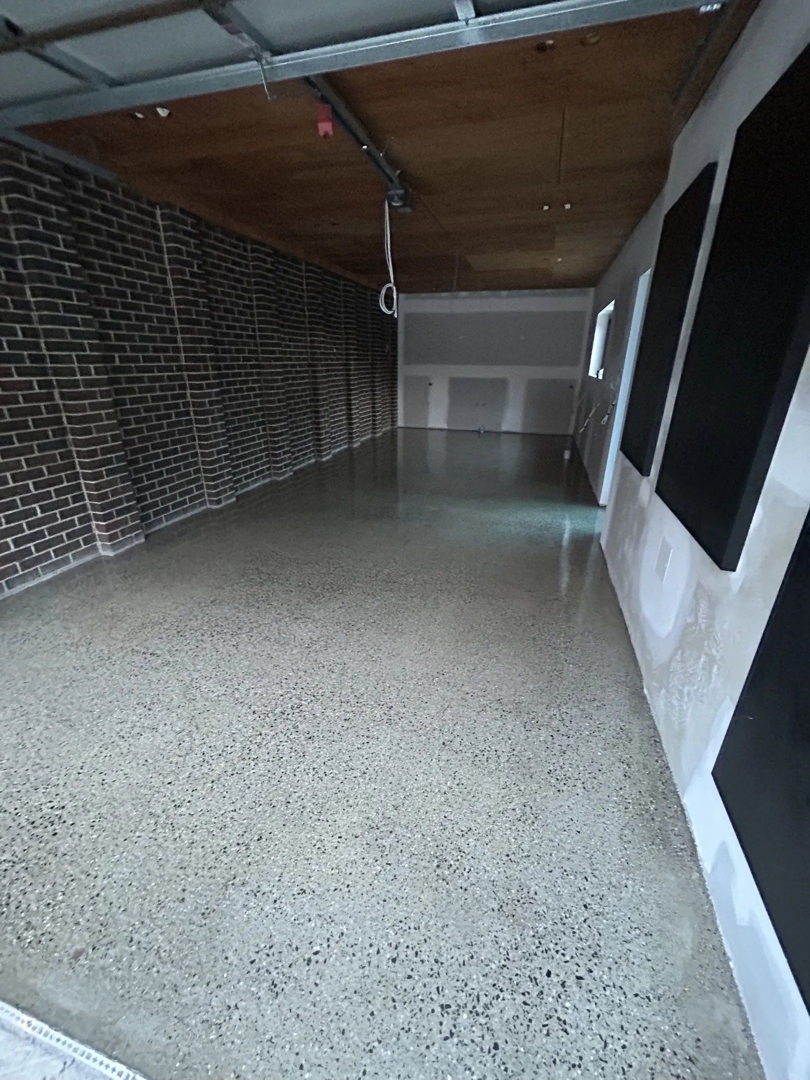 Grind and seal floor running the length of a garage with a brick wall and timber-lined ceiling