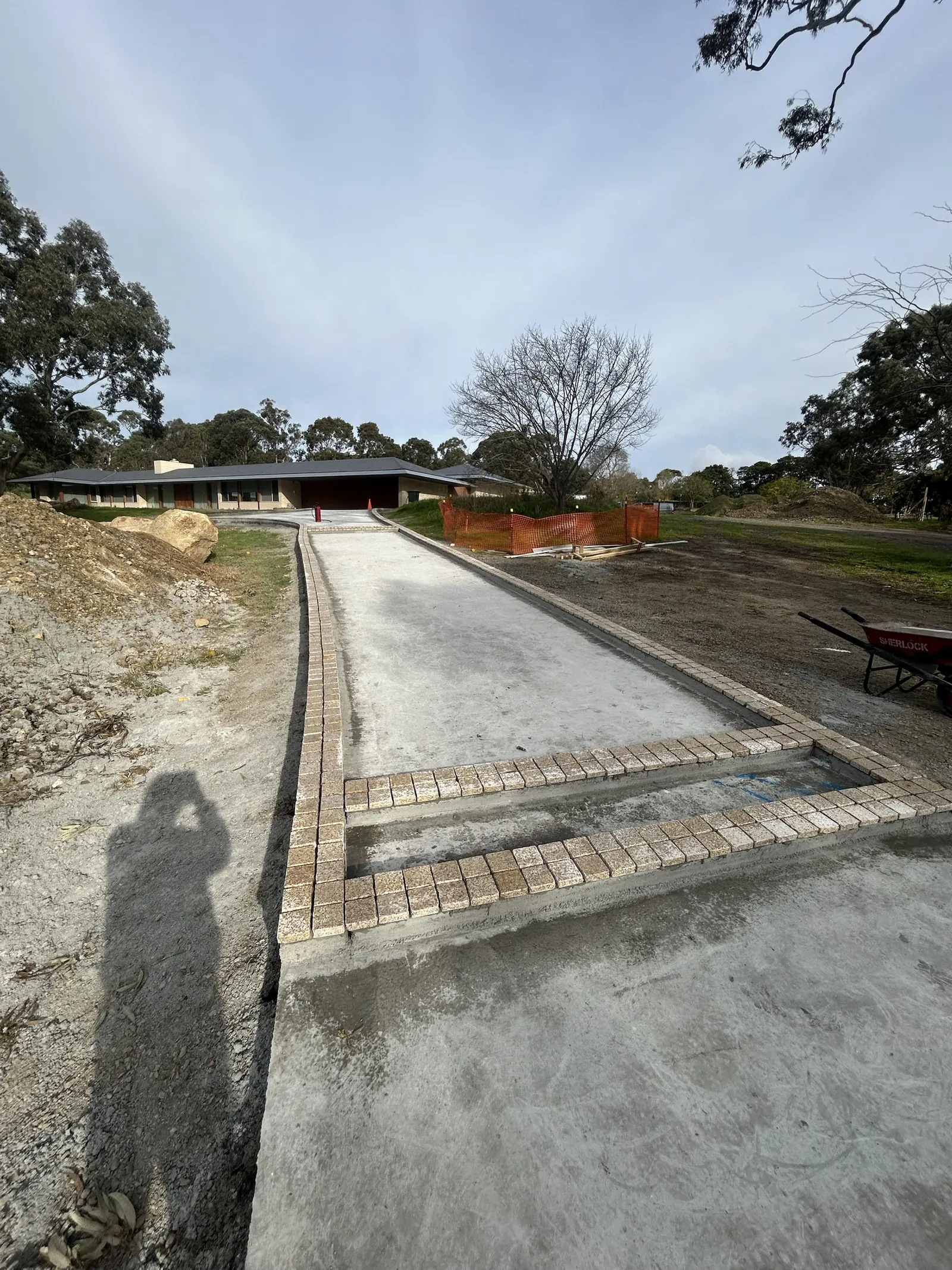 Long concrete driveway with granite cobble borders and steps, mid-job